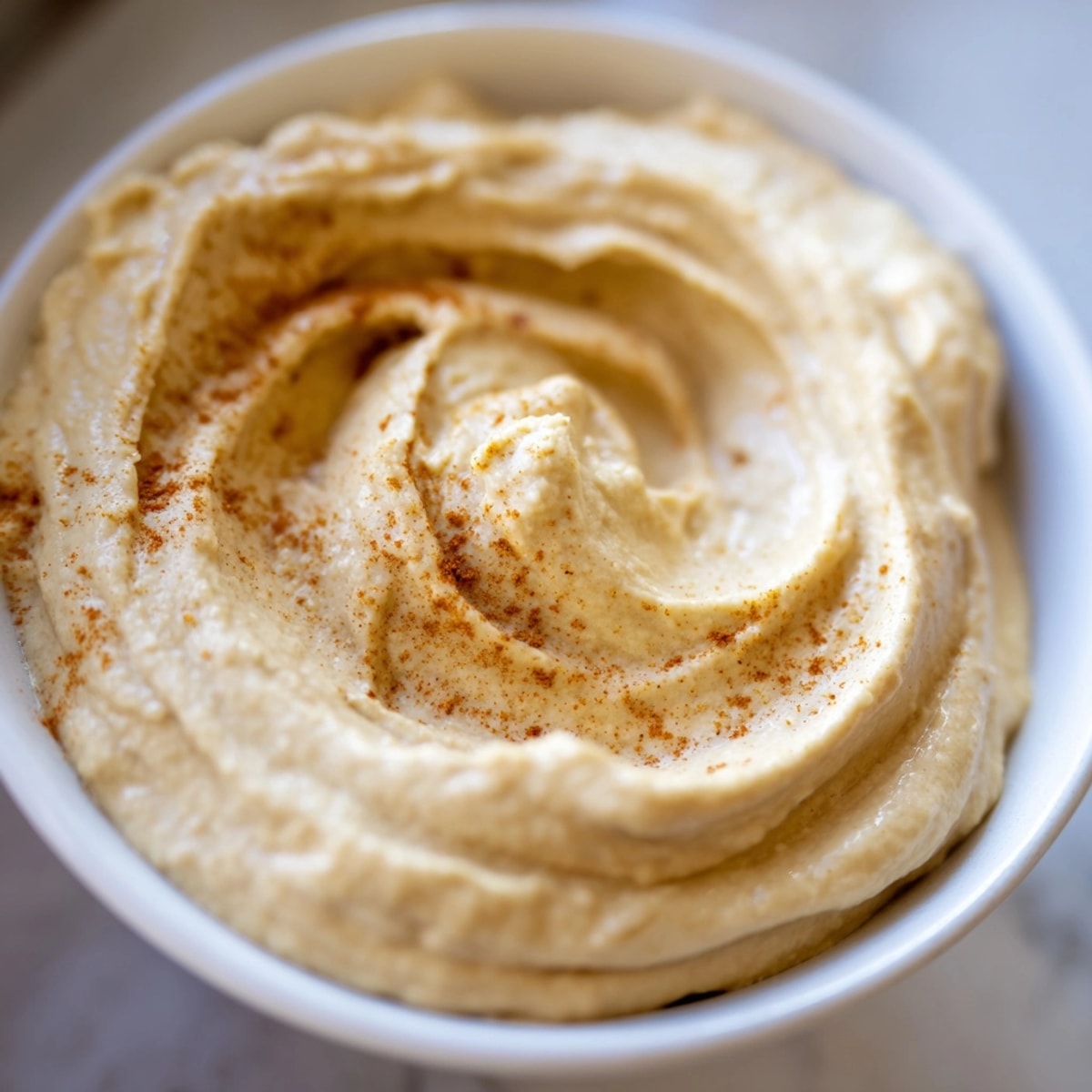 Homemade oil-free hummus: swirl of chickpea dip, ready to be scooped with pita bread.