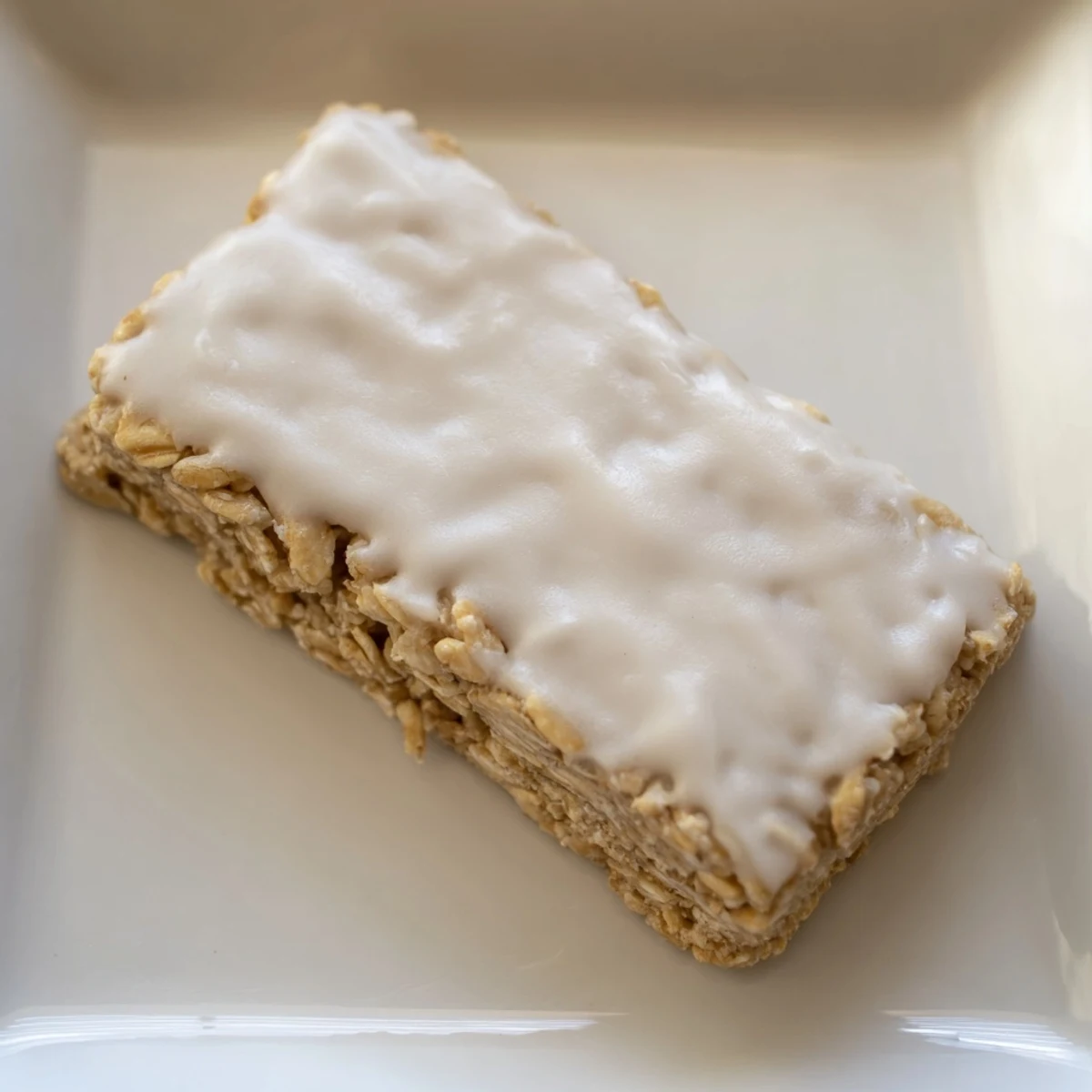 Square-cut frosted oat bars, showcasing a chewy texture and inviting vanilla flavor.
