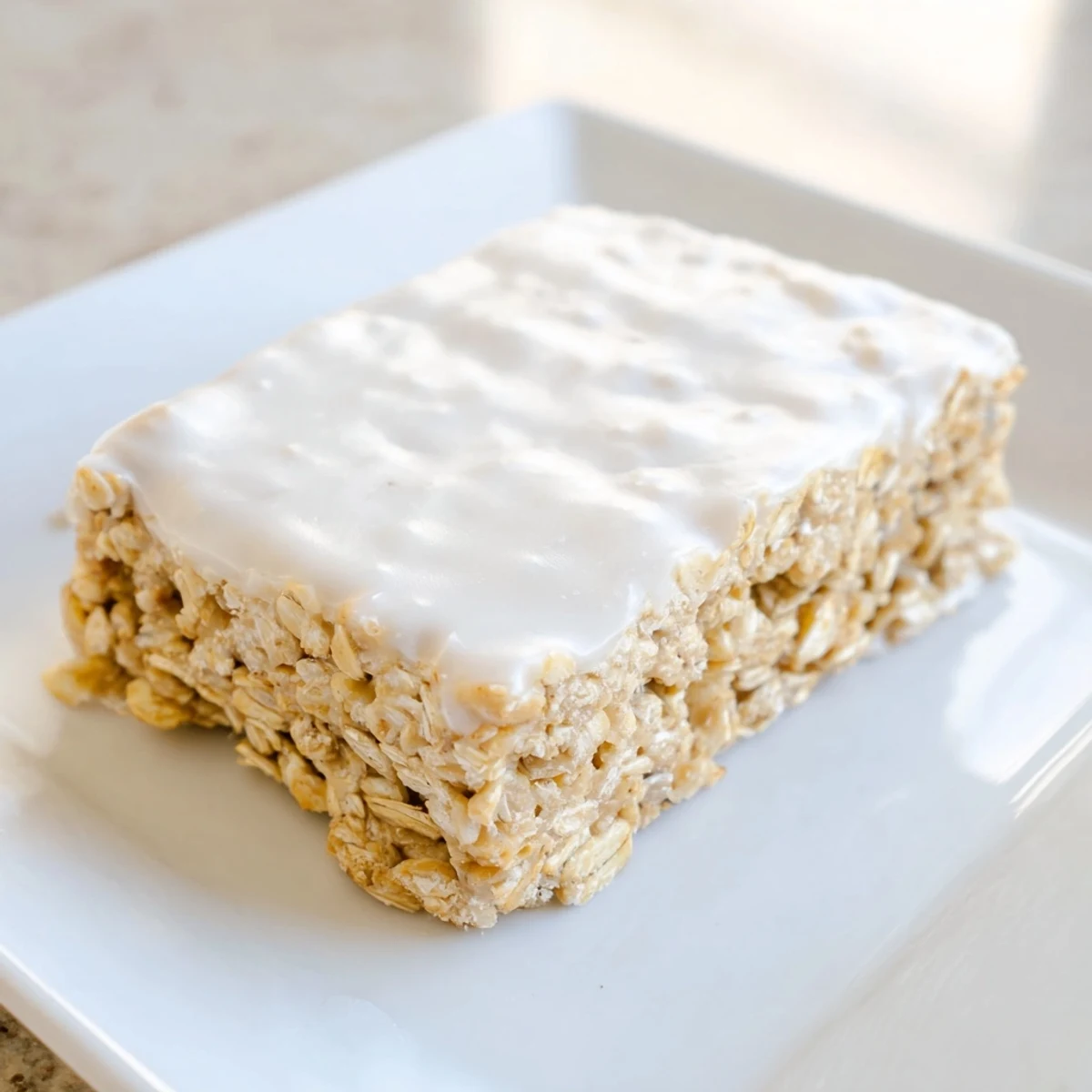Golden-brown frosted oat bars with creamy vanilla frosting, perfect for a sweet snack.