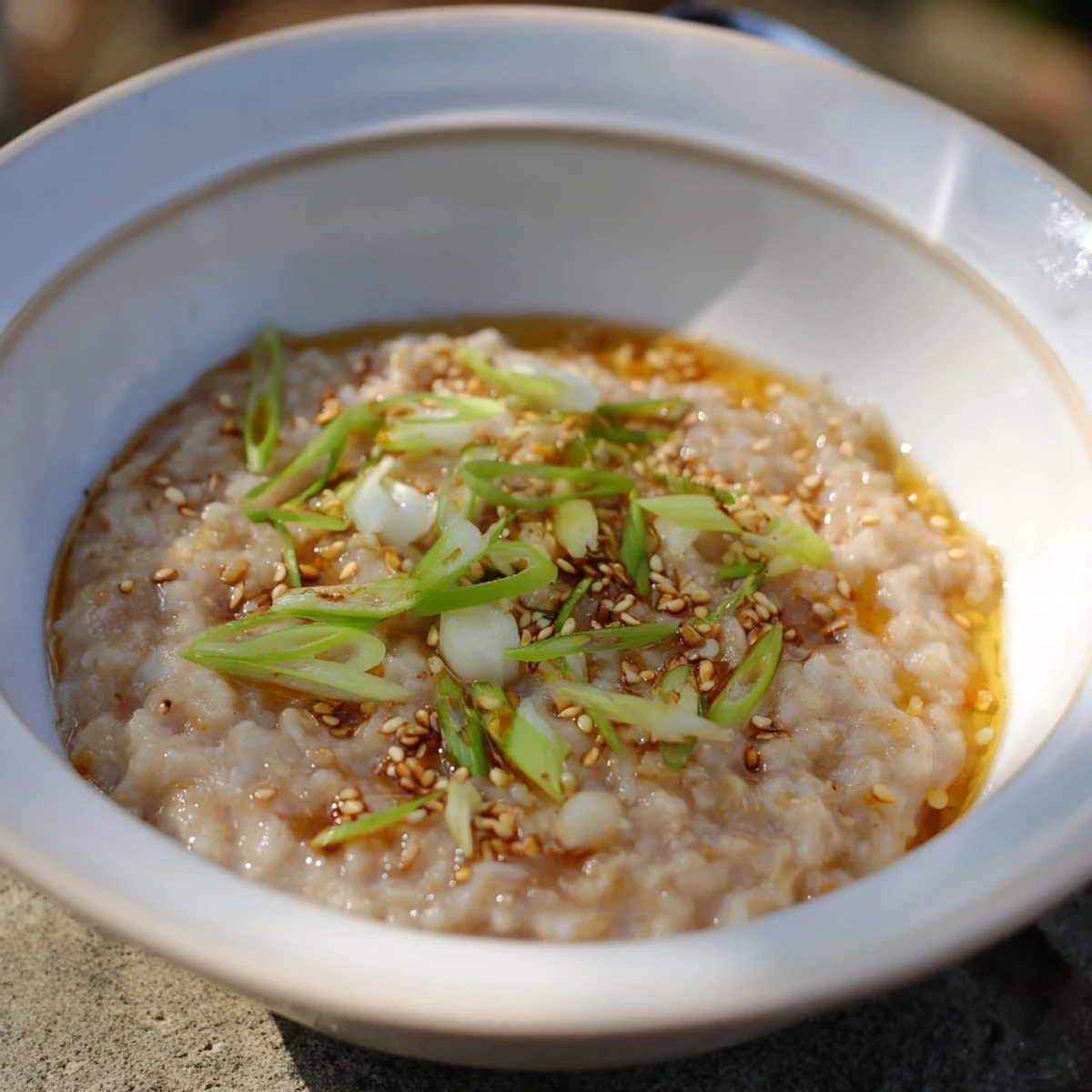 Steaming bowl of warm ginger porridge, topped with honey and fresh fruit, ready to eat.