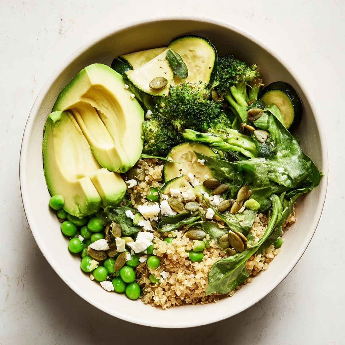 This Warm Green Bowl features tender green vegetables, flavorful grains, and a creamy avocado topping.