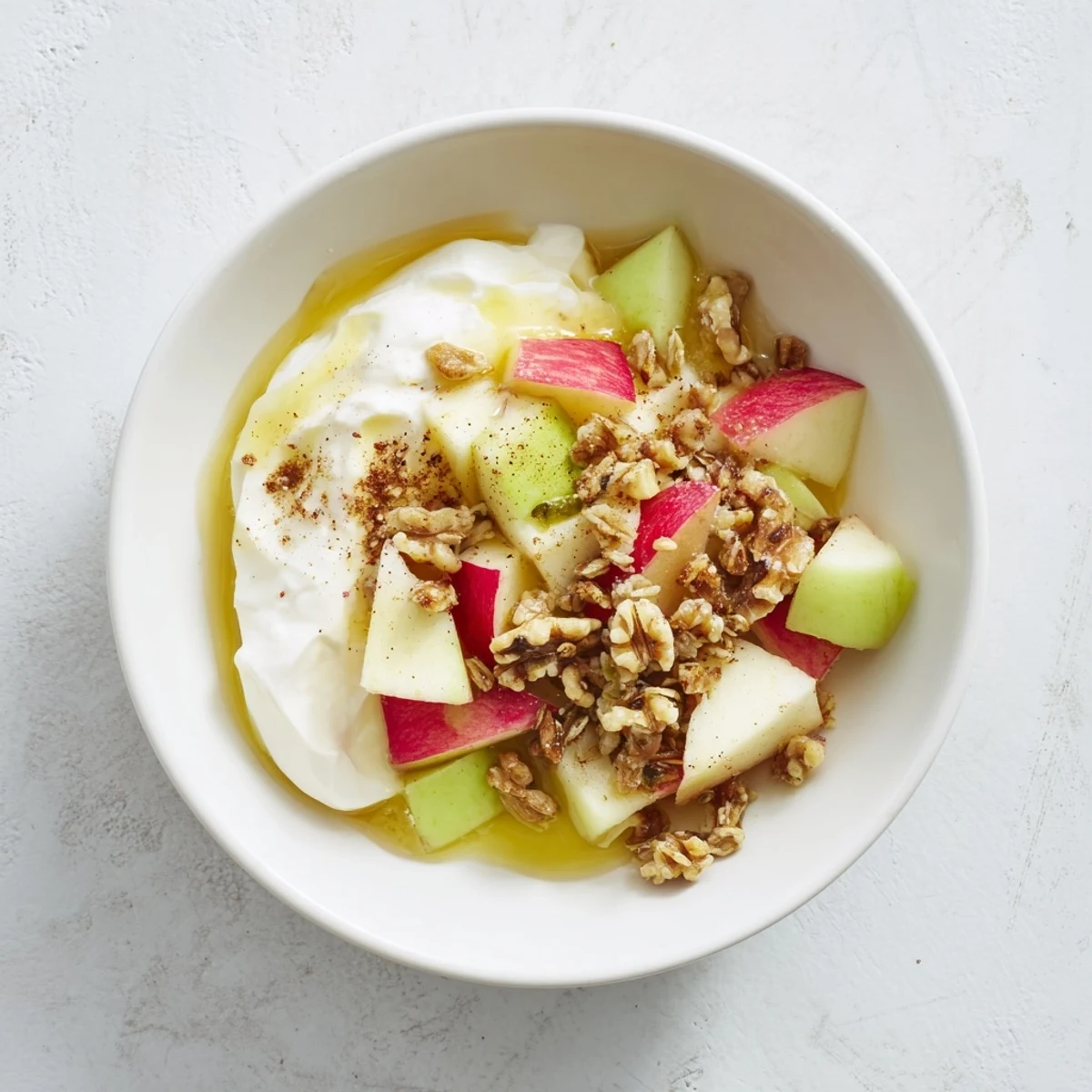 A colorful Crisp Apple Bowl with creamy yogurt, fresh apples, crunchy granola, and nuts.