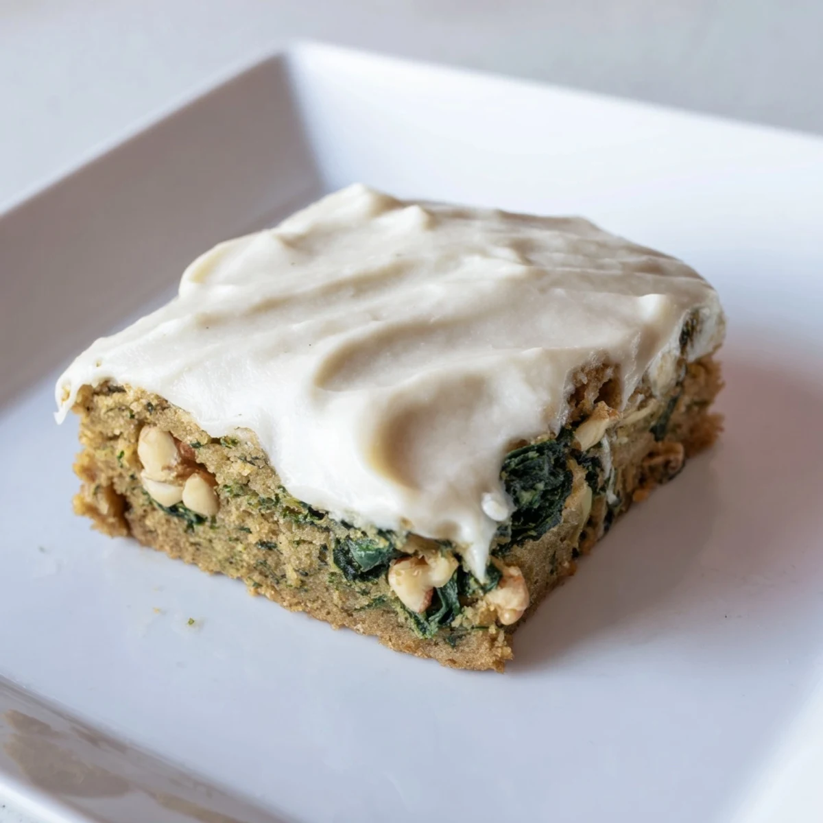 Moist Frosted Spinach Bars, a sweet treat with creamy frosting, ready to serve as a dessert.