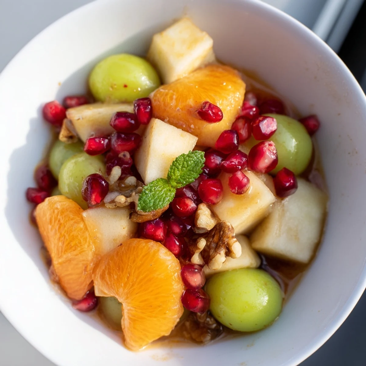 Ready-to-serve New Year Apple Bowl with kiwi slices and grapes, topped with fresh mint and walnuts for a festive touch.