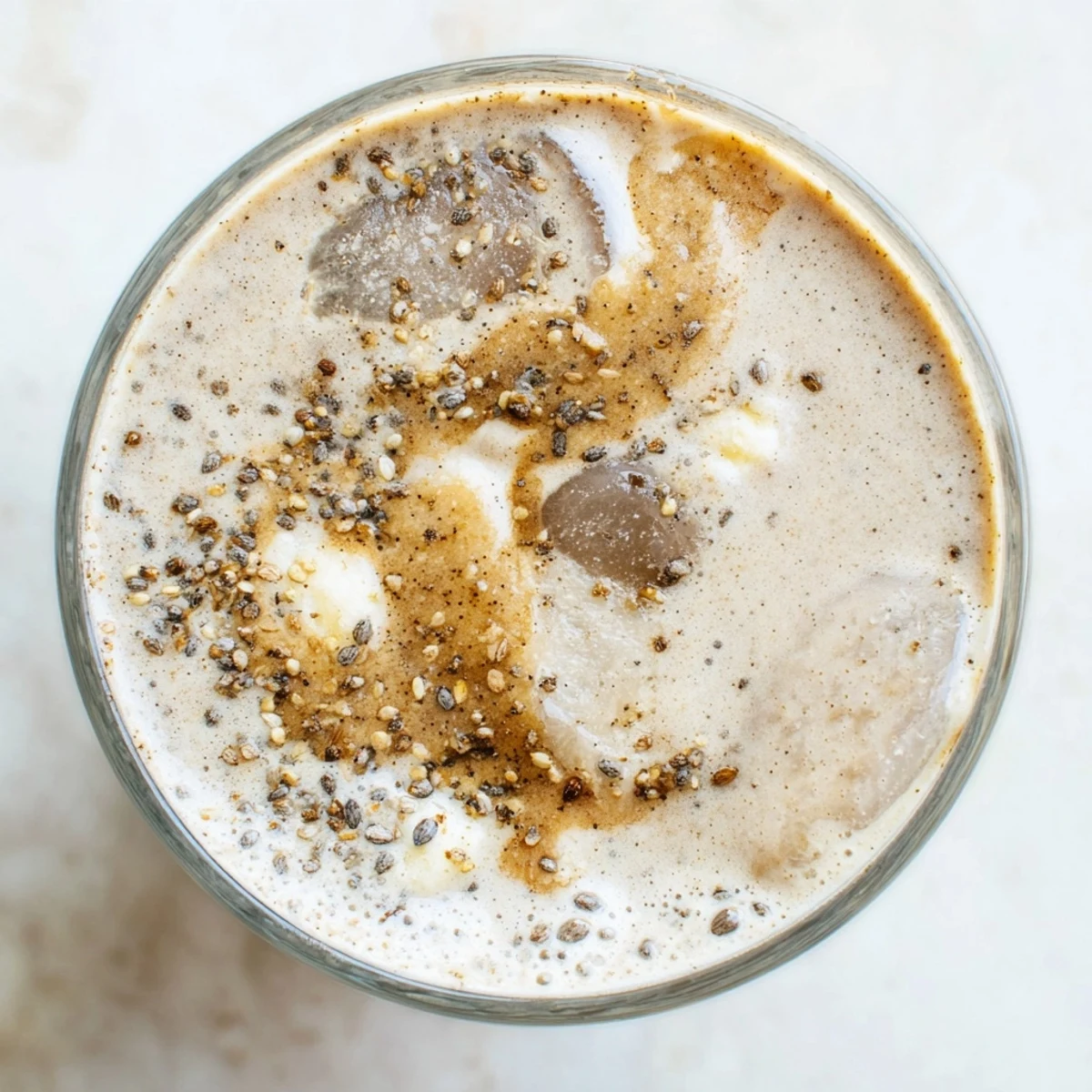 Two tall glasses of Vegan Maple Smoothie, filled with creamy golden liquid and topped with a sprinkle of cinnamon and sliced bananas.