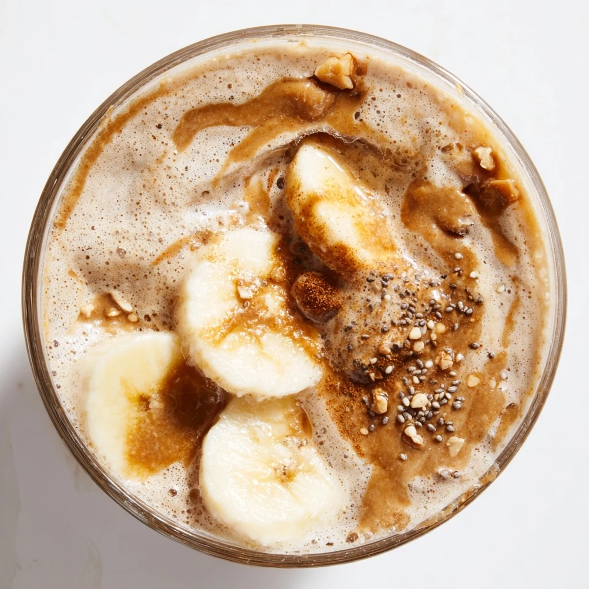 A hand holding a frosted glass of Vegan Maple Smoothie, with a breakfast bowl and granola nearby for a complete meal.