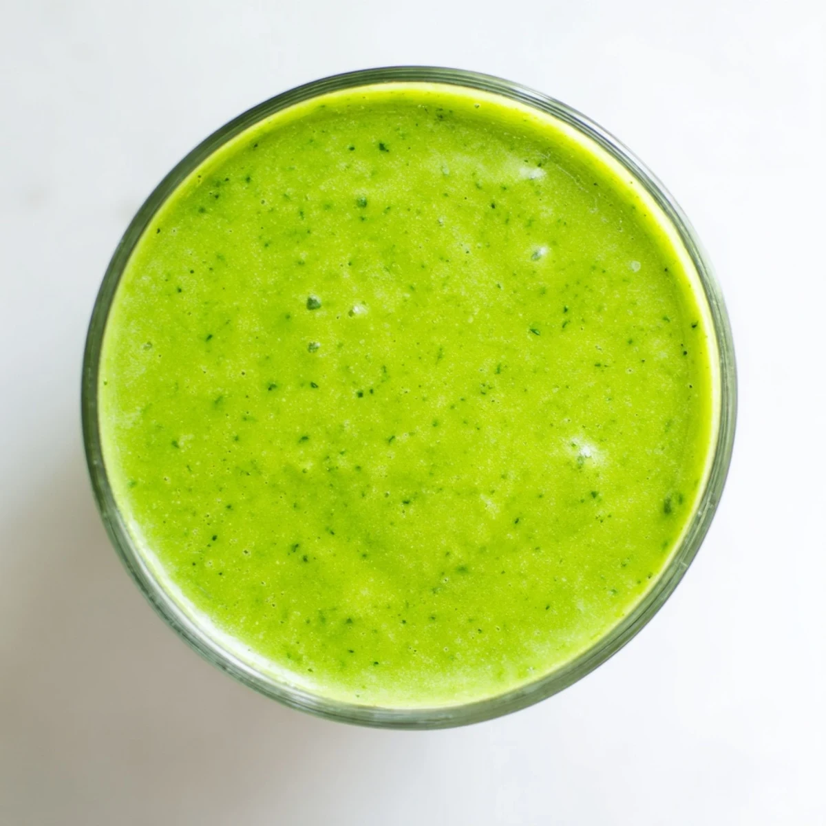 Lush green Bright Spinach Smoothie with vibrant pineapple chunks and creamy yogurt, poured and ready to enjoy.
