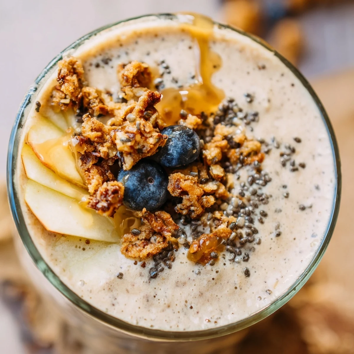 A close-up of a glass of Seasonal Maple Smoothie, showing a thick, frothy texture swirled with pure maple syrup.