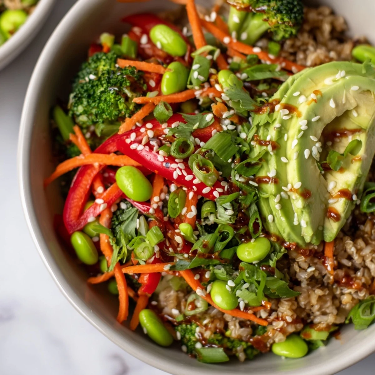 Vibrant edamame and red bell pepper garnish this plant-based Fresh Ginger Bowl, served alongside creamy avocado slices and fresh green onions.