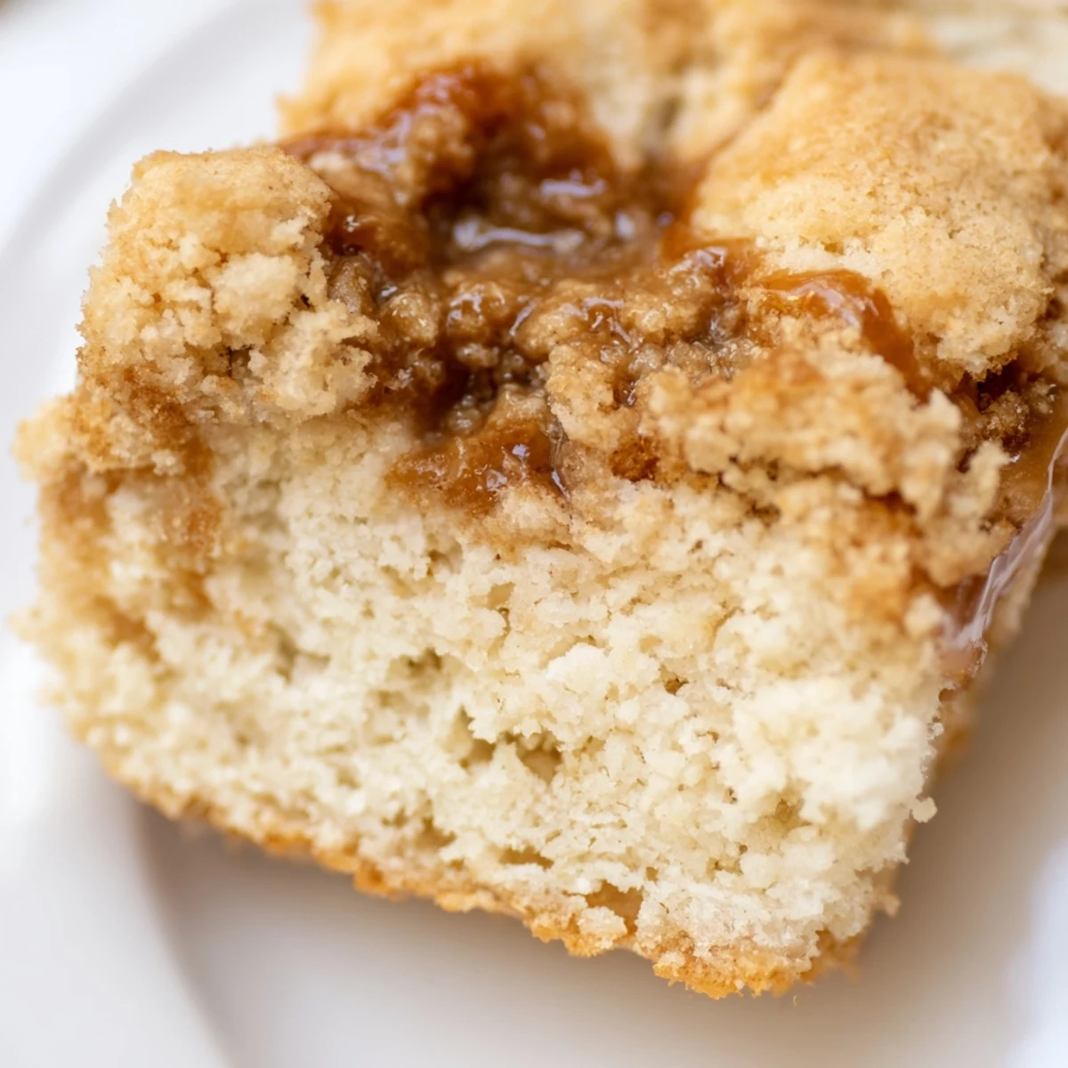A close-up of freshly baked Cozy Maple Bars showing their soft, cake-like texture and glossy maple glaze.