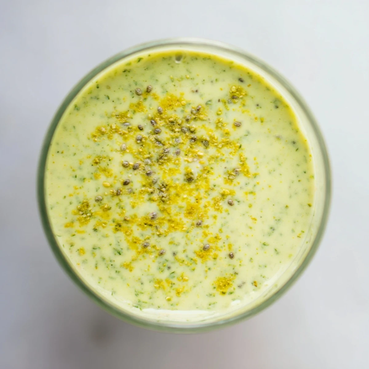 A tall glass of the Wholesome Ginger Smoothie, filled with bright green spinach and a frothy, creamy texture from banana and pineapple.