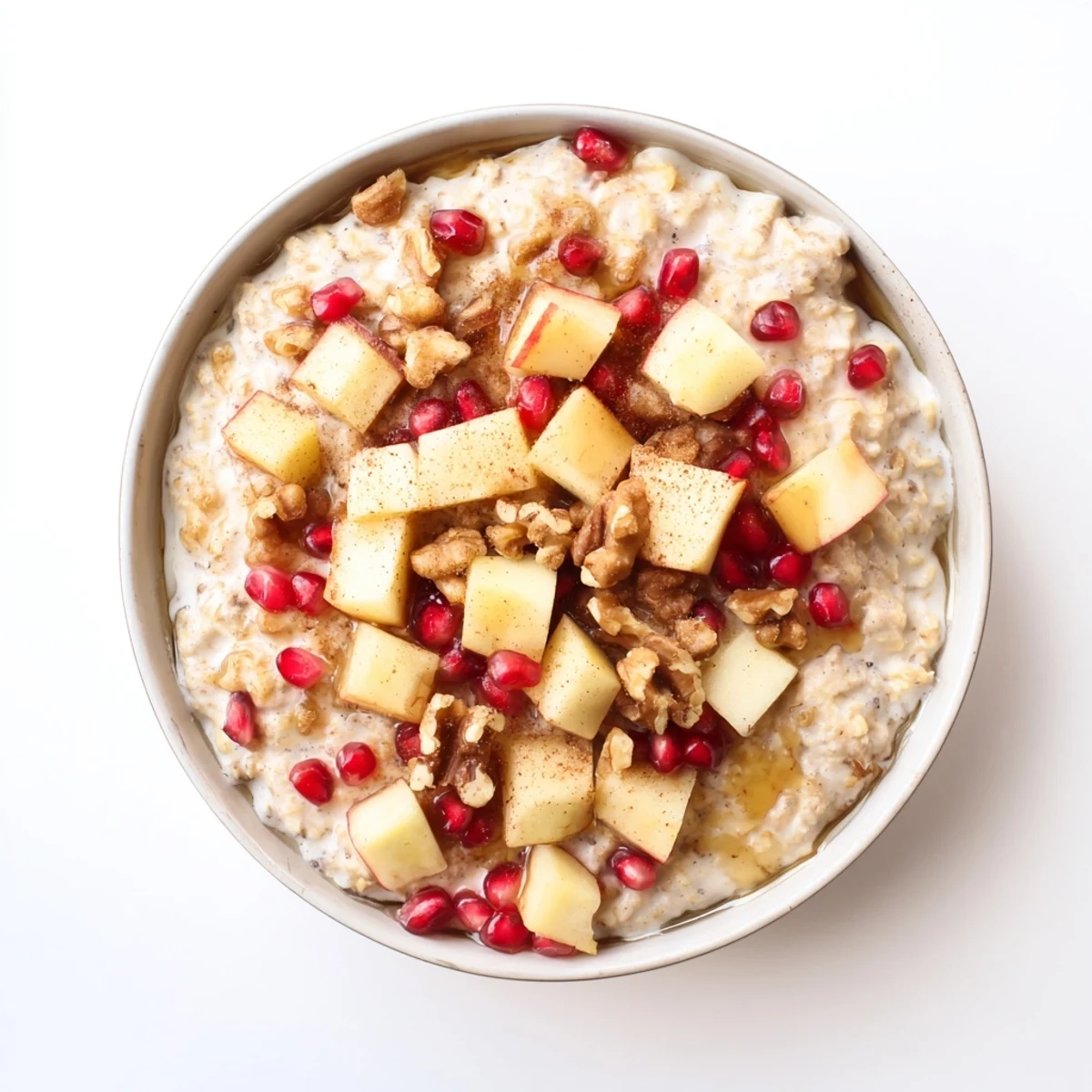 Creamy New Year Maple Porridge with diced apples, pomegranate seeds, and crunchy walnuts in a cozy breakfast bowl.  