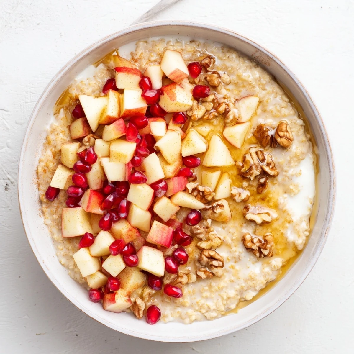 A spoonful of warm New Year Maple Porridge topped with sweet maple syrup drizzle, cinnamon, and seasonal fruits.  