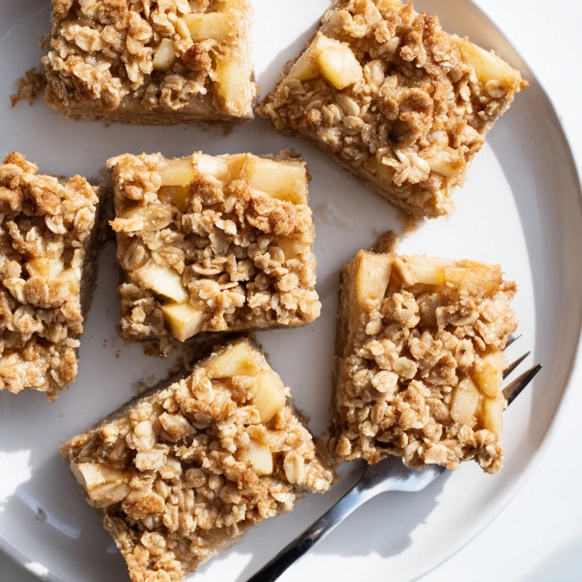 A close-up of golden Wholesome Pear Bars, showing juicy pear chunks and an oat crumble topping on a rustic wooden board.