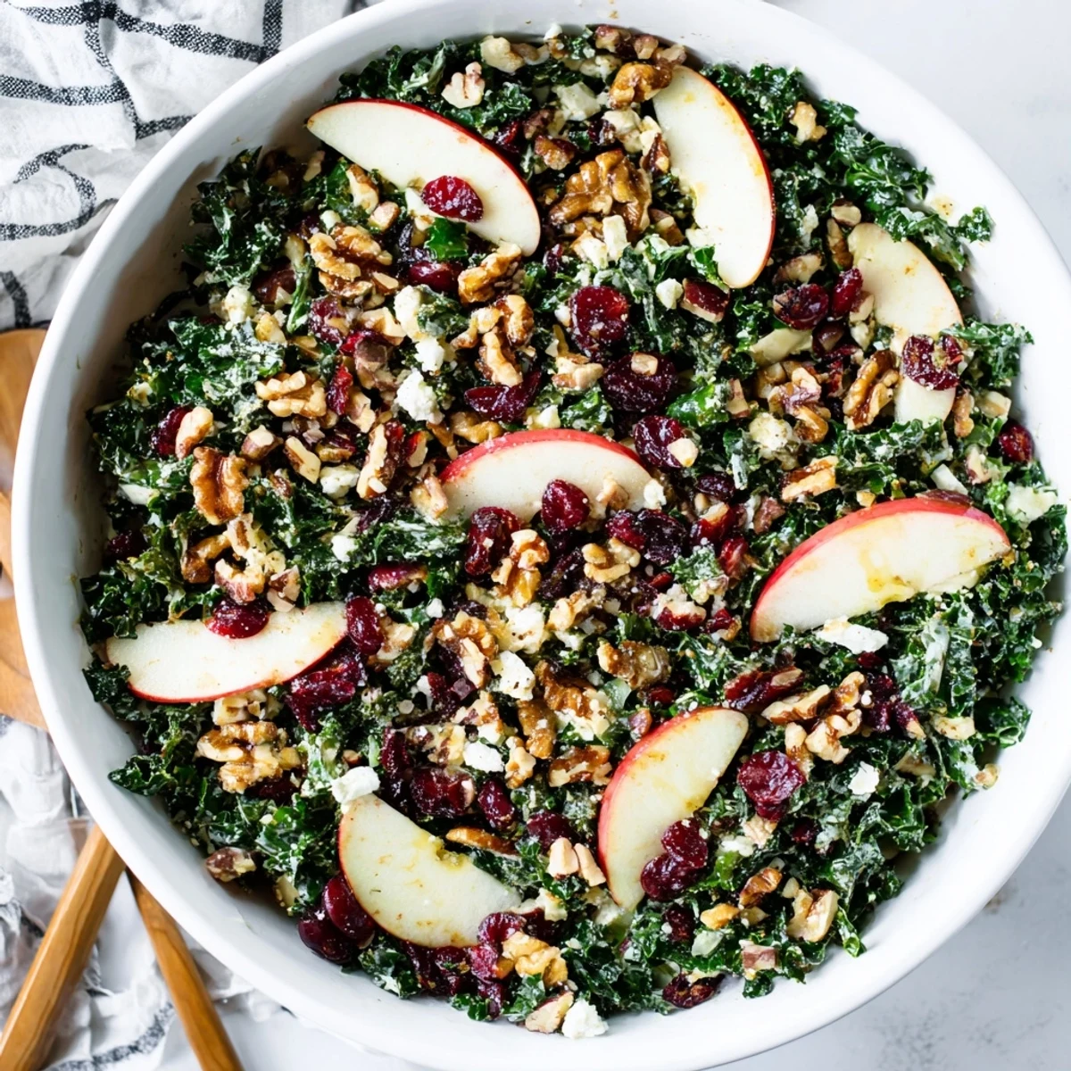 A vibrant New Year Kale Treat salad with crisp kale leaves, sliced sweet apples, and crunchy walnuts on a wooden salad bowl.