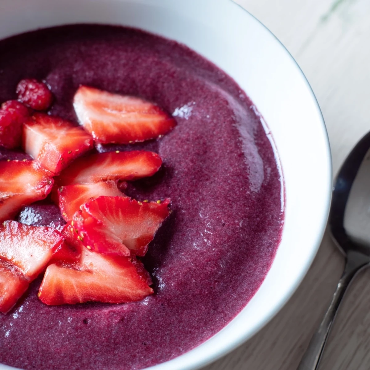 Overhead shot of Vegan Berry Soup in a clear glass, topped with extra berries and a mint leaf, perfect for a light dessert.