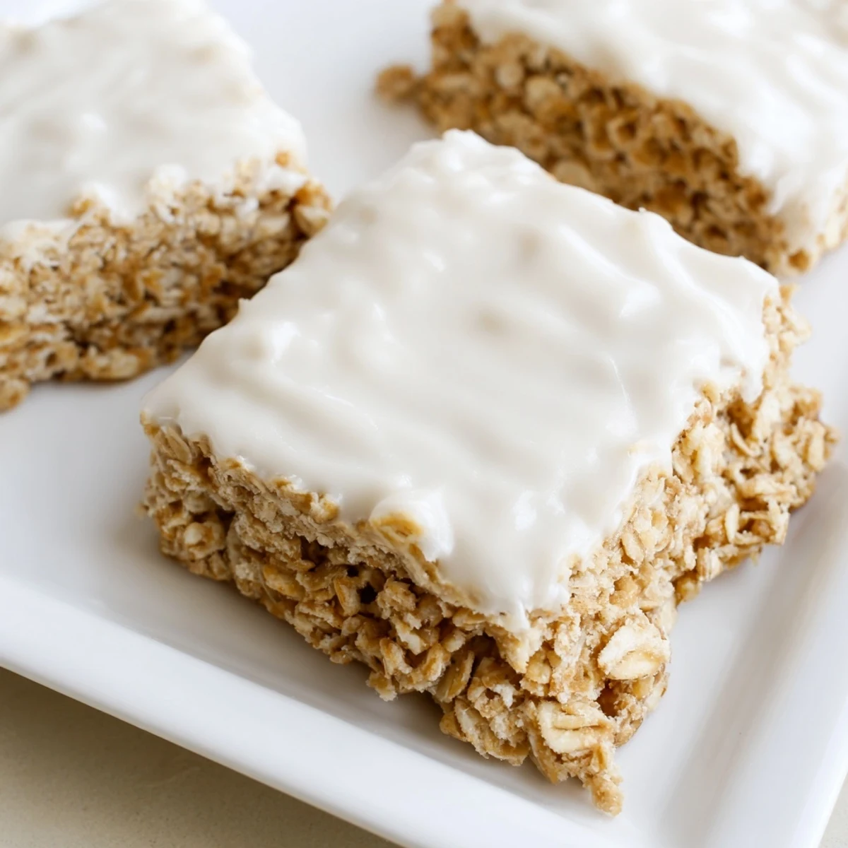 Close-up of Frosted Oat Treat bars showing chewy texture and glossy sweet frosting, ideal for dessert.  