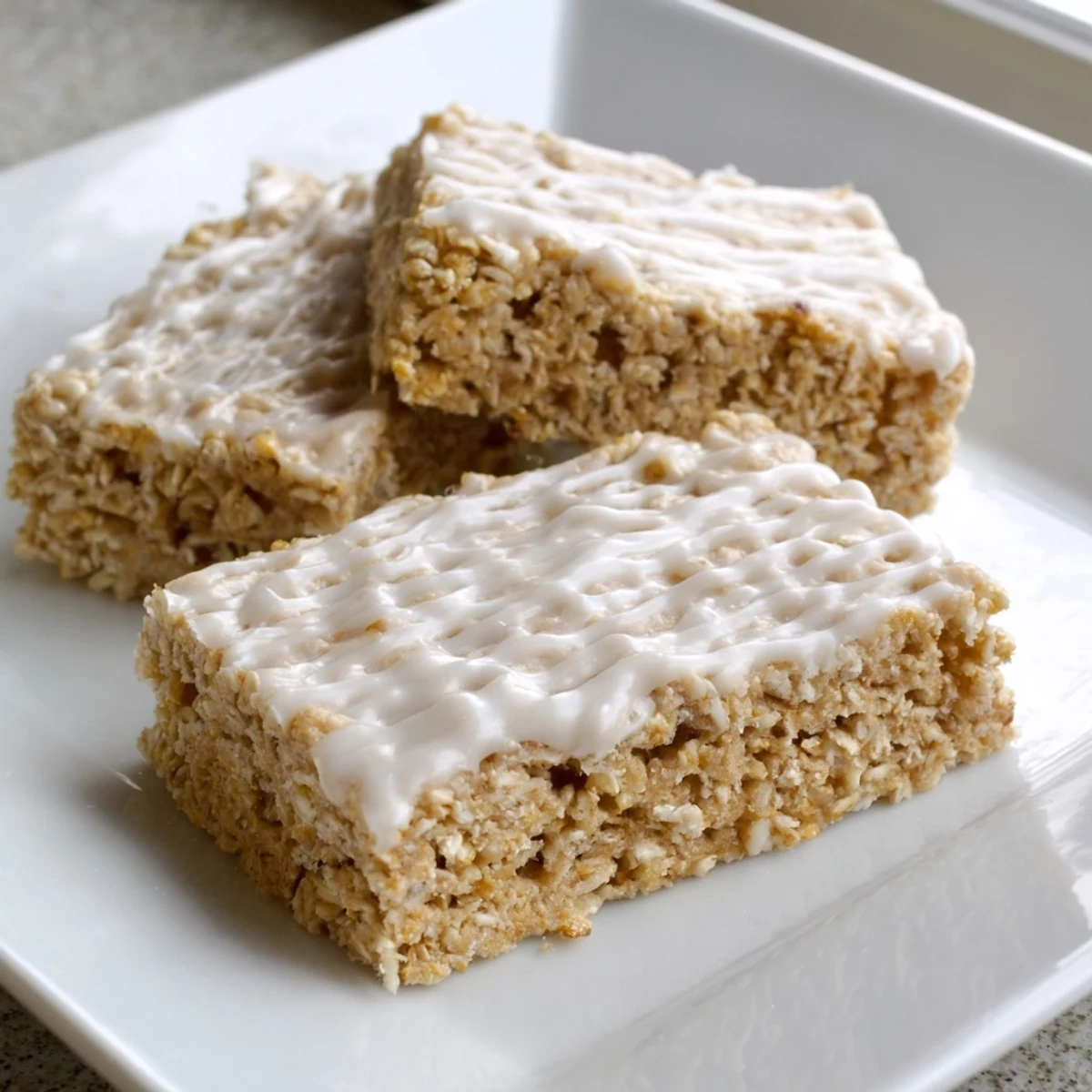 Homemade Frosted Oat Treat bars cut into squares with a drizzled vanilla glaze, perfect for snacking.