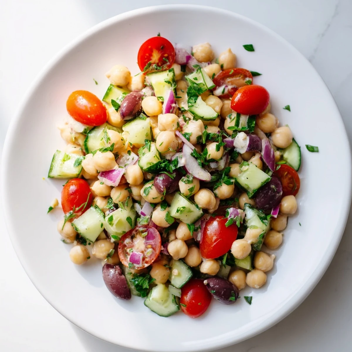 Vegan Chickpea Salad with bright cherry tomatoes and cucumber, tossed in a creamy lemon-tahini dressing for a fresh Mediterranean lunch.