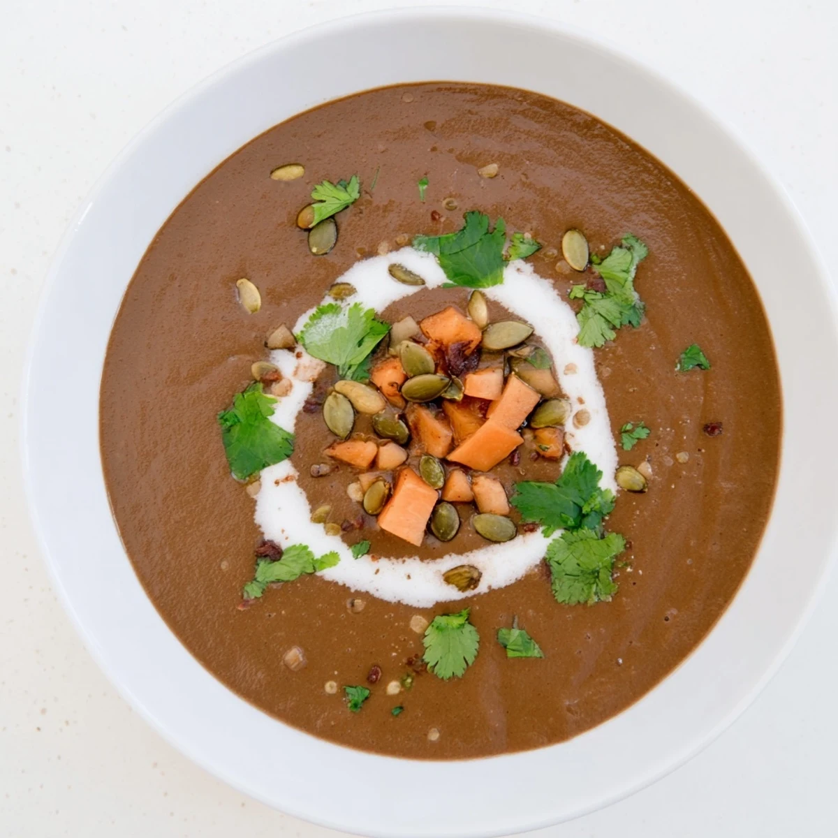 A warm bowl of Seasonal Cacao Soup garnished with toasted pumpkin seeds and fresh herbs.