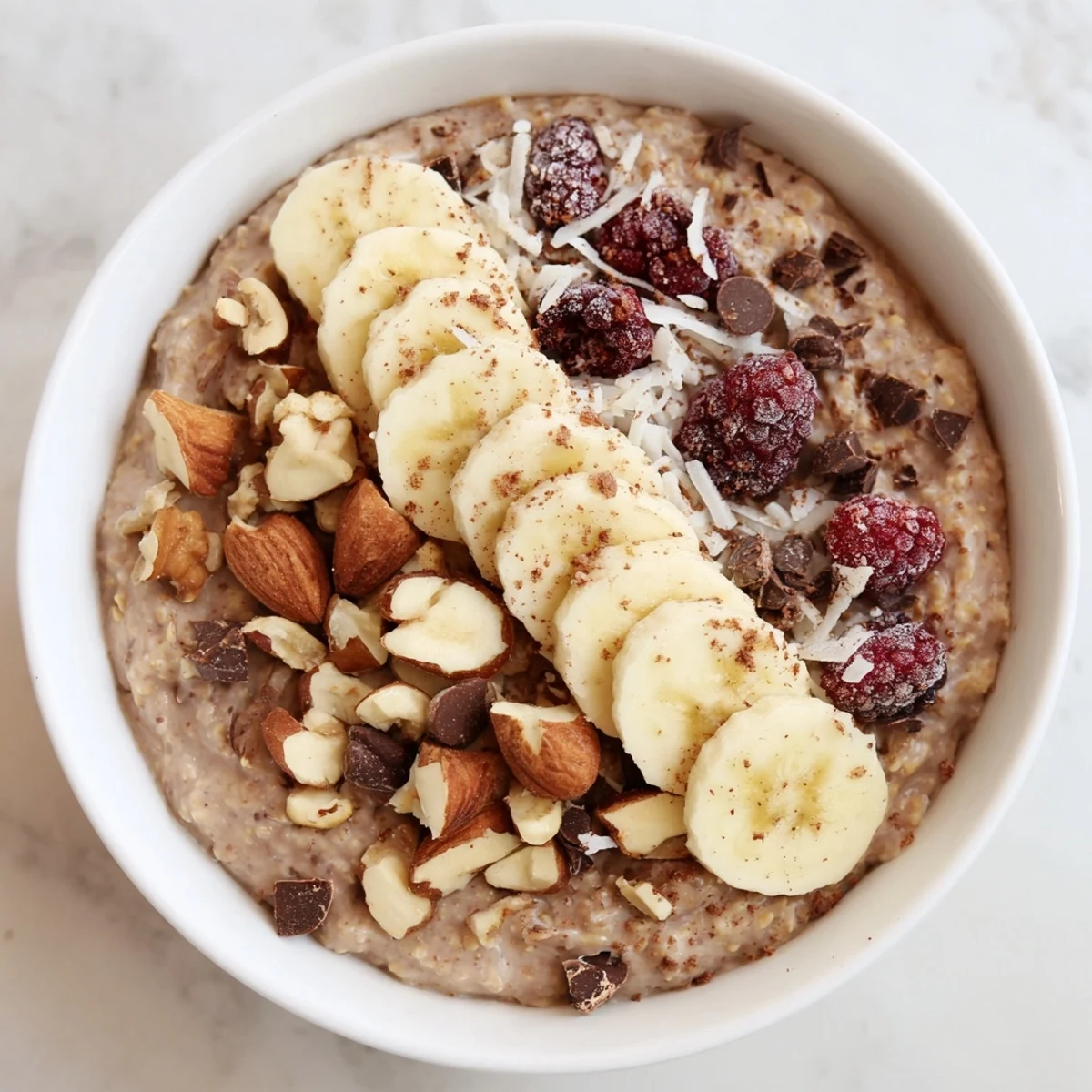 Creamy wholesome cacao porridge in a warm bowl, topped with banana slices, almonds, and berries for a nourishing breakfast.