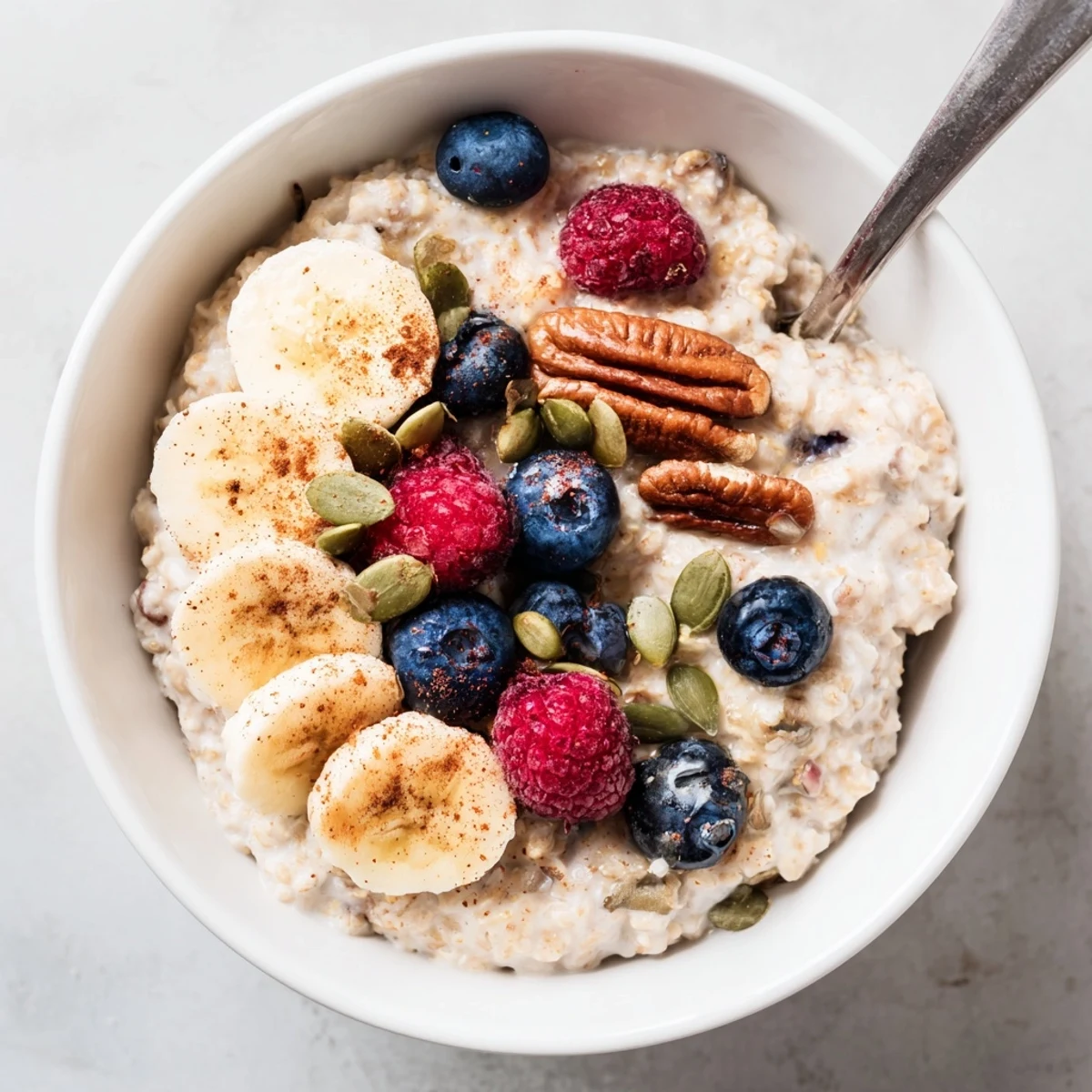 A warm, comforting serving of Vegan Maple Porridge with a swirl of maple syrup, cinnamon, and mixed berries on top.
