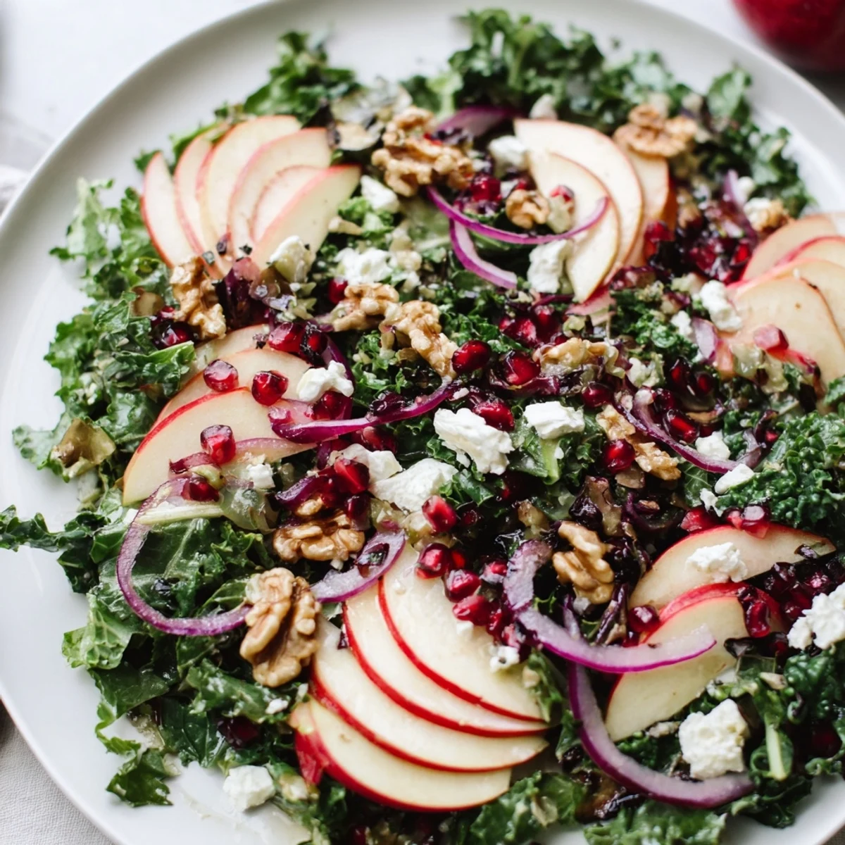 Bright, fresh Winter Apple Salad with crisp apple slices, kale, and walnuts, topped with crumbled feta and pomegranate seeds.