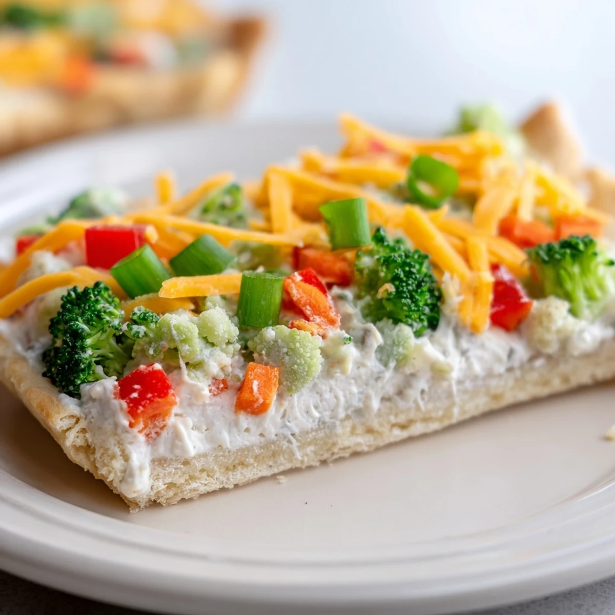 Fresh Veggie Bars display a golden crescent crust topped with creamy ranch spread and colorful chopped vegetables, served chilled as party finger food.  