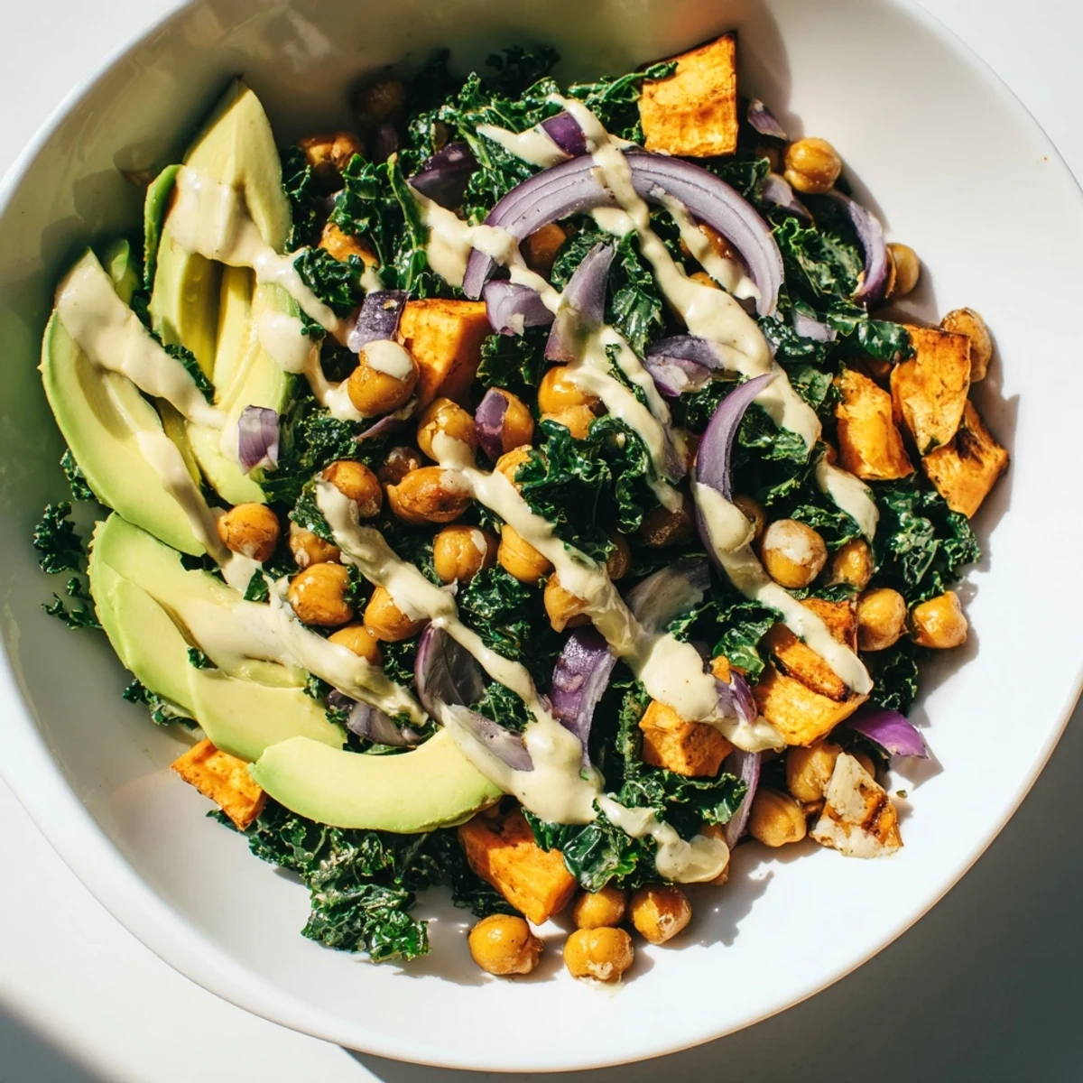 Bright, wholesome Cozy Kale Bowl with roasted sweet potatoes, sautéed kale, and chickpeas, finished with a drizzle of creamy tahini dressing.
