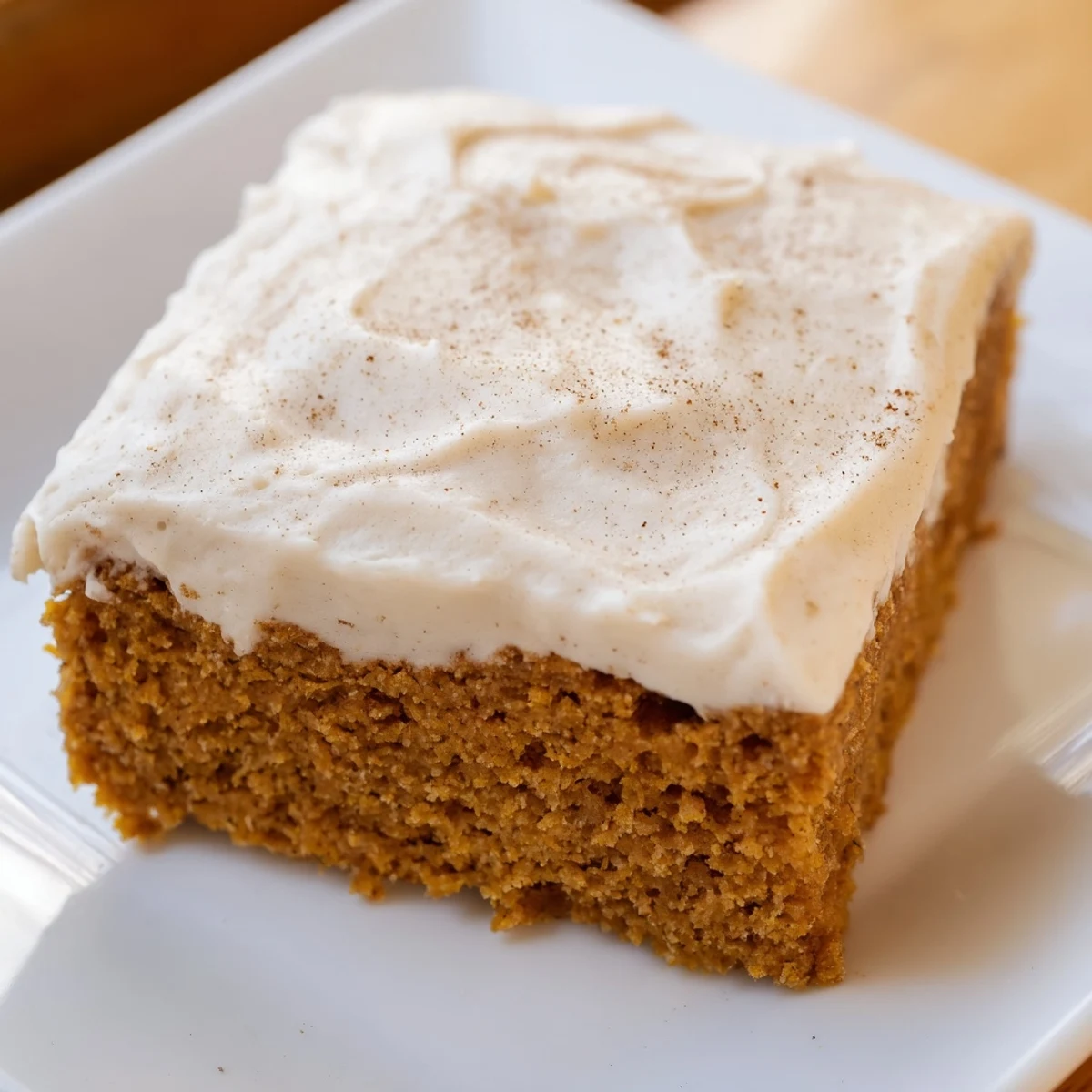 A close-up view of Frosted Pumpkin Bars, showcasing the moist, spiced pumpkin crumb topped with rich, smooth cream cheese frosting.