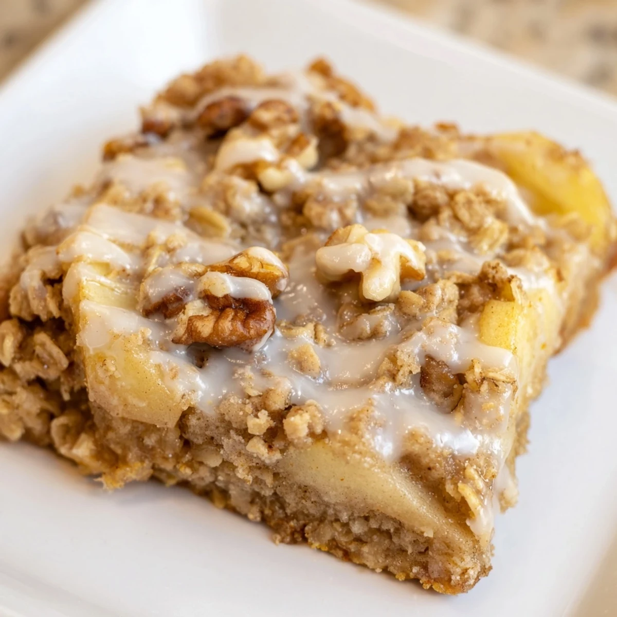 A close-up of Frosted Apple Treat with warm baked apples and a drizzle of vanilla glaze, served in a rustic dish.