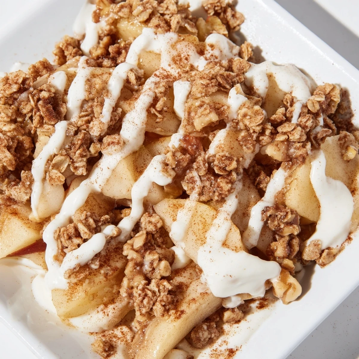 A slice of Frosted Apple Treat on a plate beside vanilla ice cream, drizzled with sweet frosting for serving.