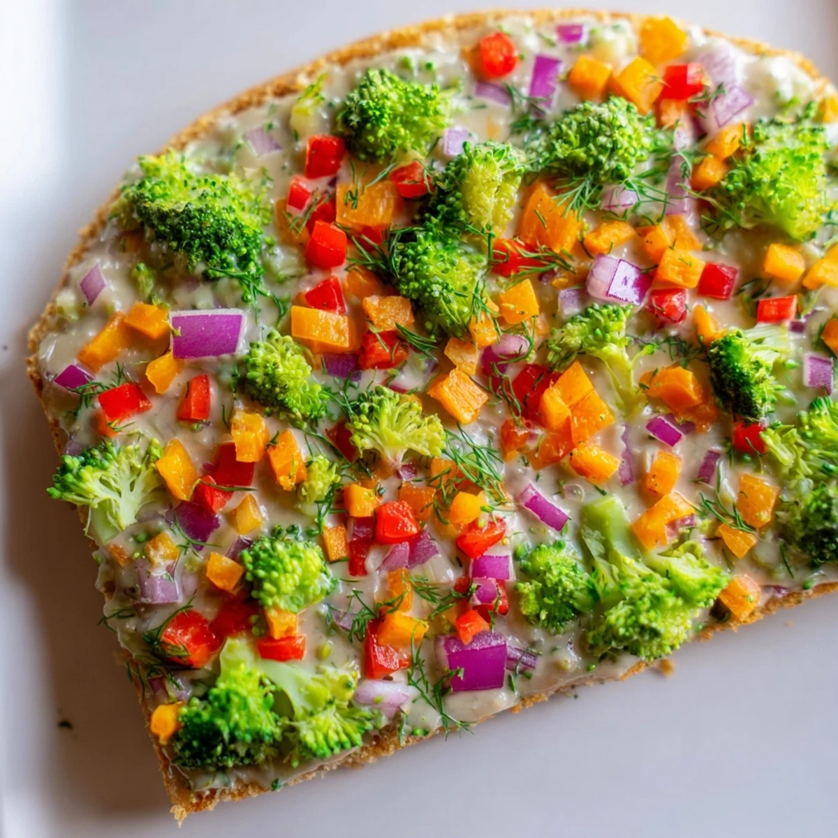 Freshly baked Frosted Veggie Bars display colorful broccoli, red pepper, and carrots atop a creamy tangy frosting.