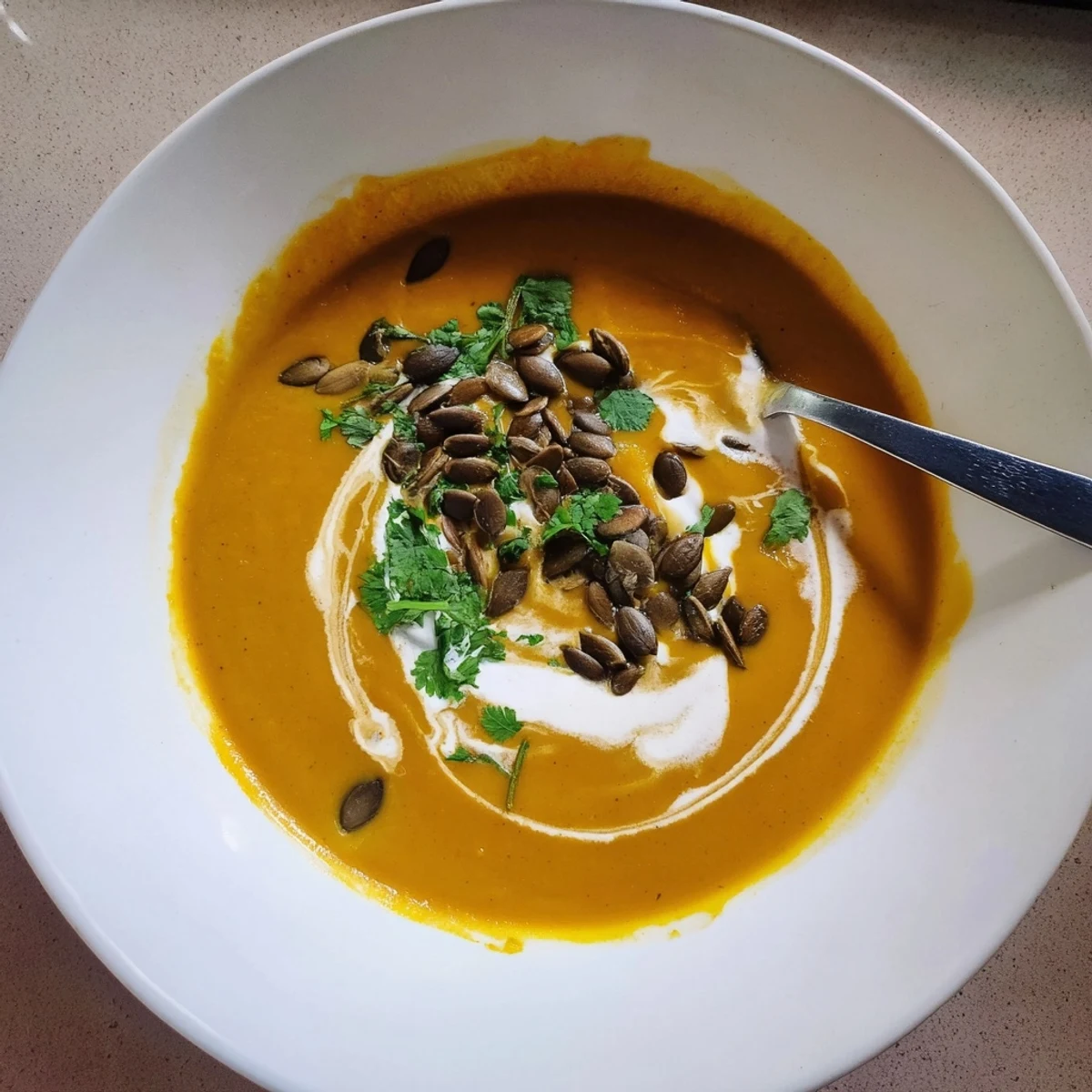 Creamy Spiced Pumpkin Hearty Soup with Coconut in a rustic bowl, garnished with toasted seeds and herbs.