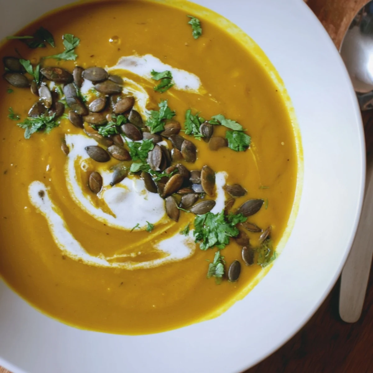 A warm serving of Spiced Pumpkin Hearty Soup with Coconut, accompanied by crusty bread for dipping on a cozy table.