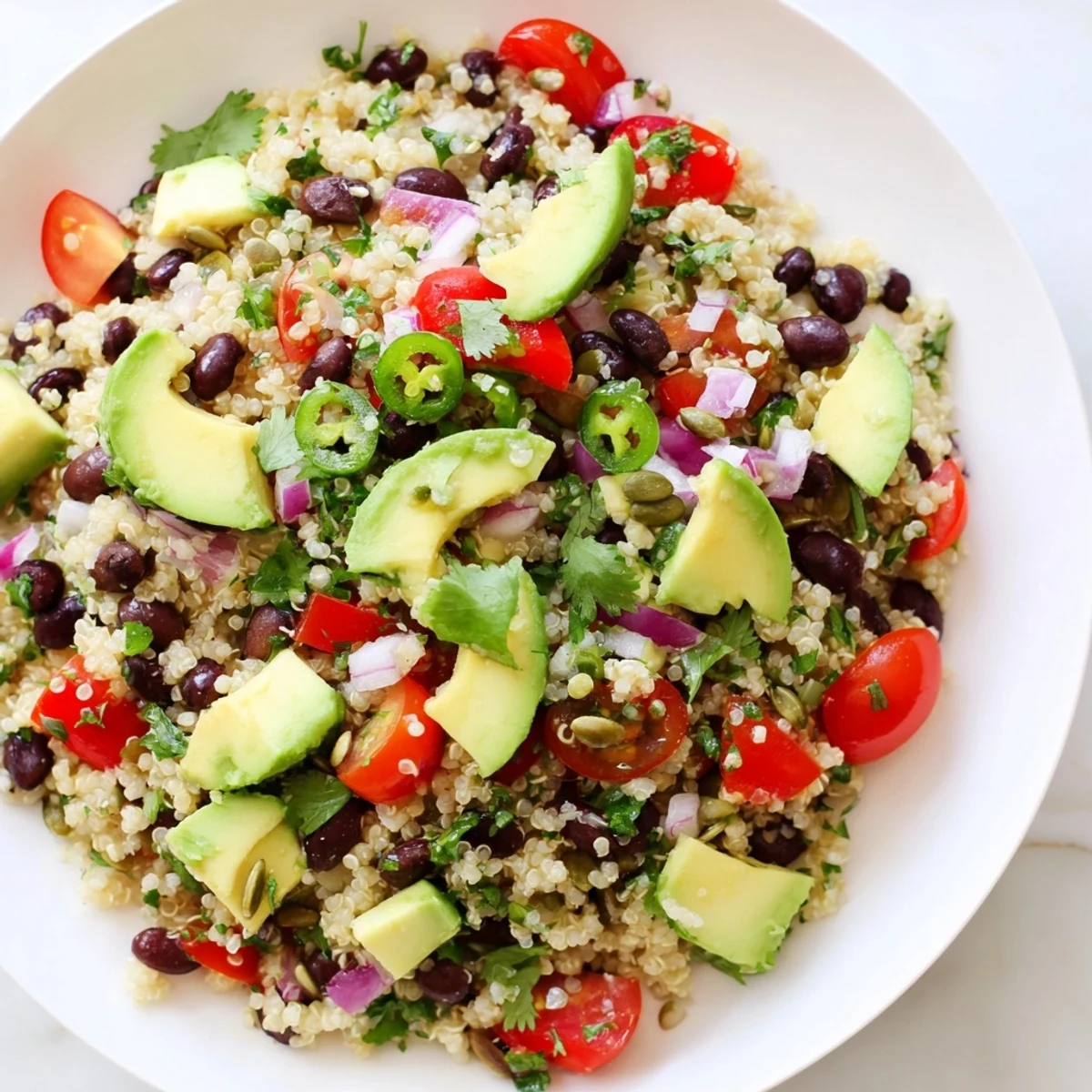 A vibrant bowl of Smoky Black Bean and Millet Grain Salad with diced avocado and toasted pepitas on a rustic table.