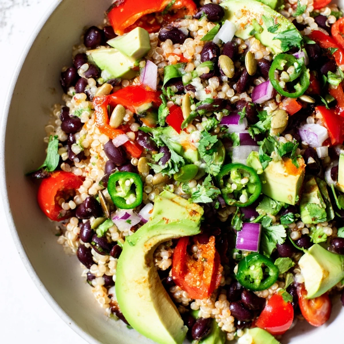 A freshly prepared Smoky Black Bean and Millet Grain Salad served chilled in a ceramic bowl with lime wedges.