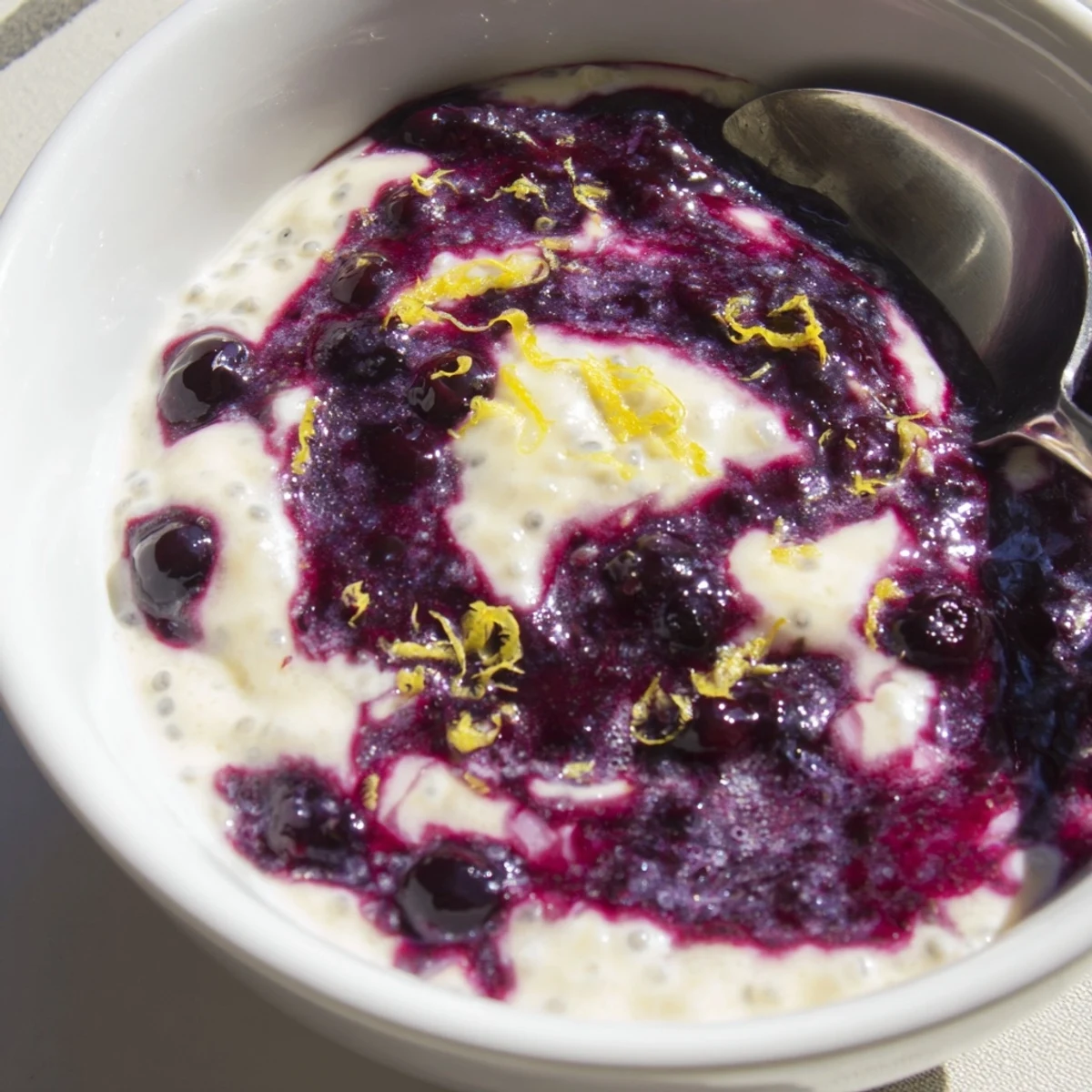 Freshly made Blueberry Lemon Cheesecake Chia Breakfast Bowl topped with granola and lemon zest.