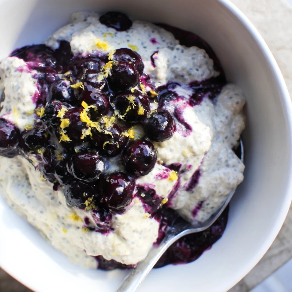 Vibrant Blueberry Lemon Cheesecake Chia Breakfast Bowl served in a white ceramic bowl with graham crumbs.