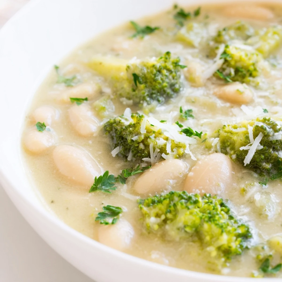 Steam rises from this Creamy Broccoli White Bean Hearty Soup served in a rustic white bowl.  