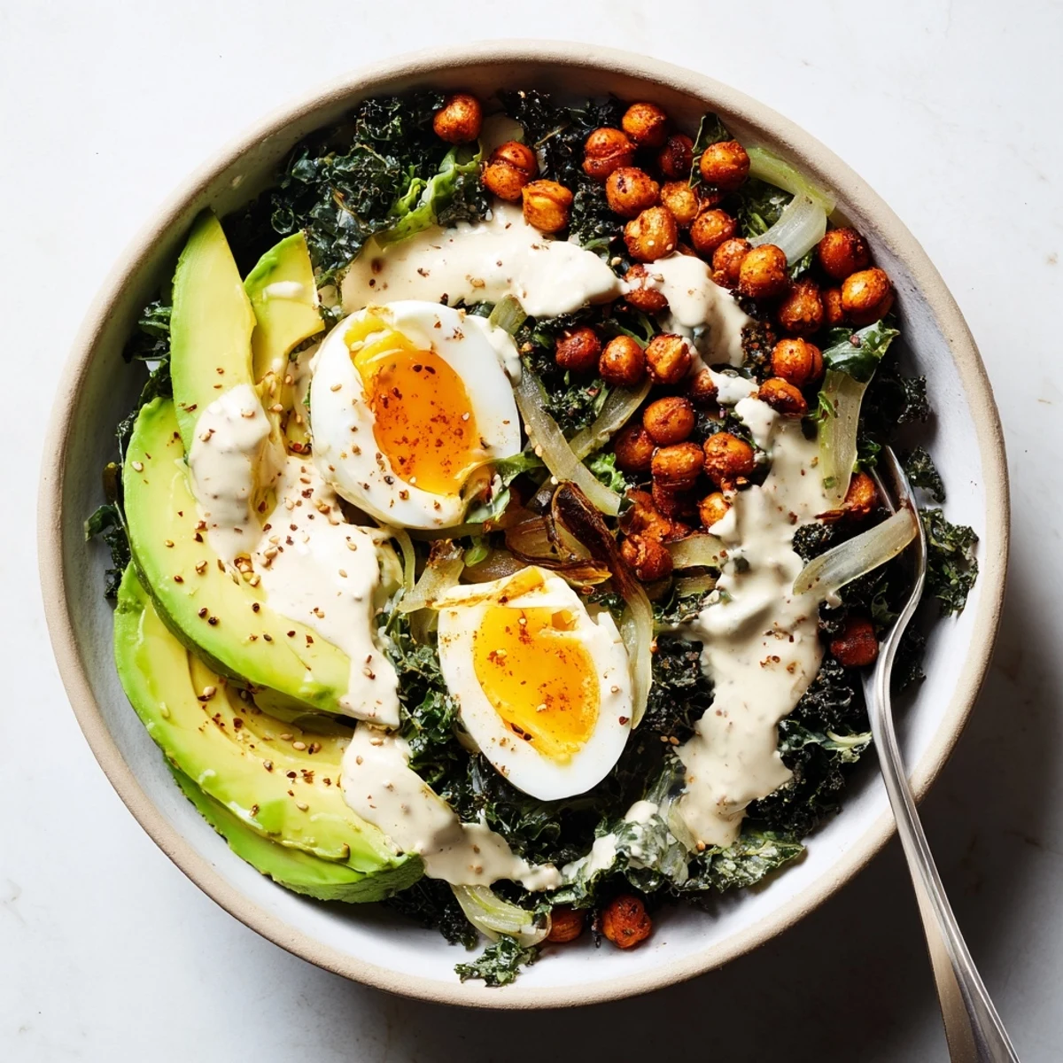 Creamy tahini dressing and soft-boiled egg top the Savory Tahini Kale Breakfast Bowl with Crispy Chickpeas