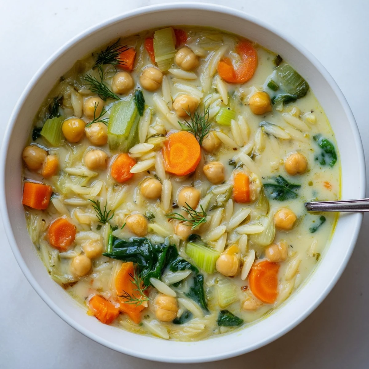 Vibrant pot of Creamy Lemon Chickpea Orzo Hearty Soup with chickpeas, orzo, and fresh dill.