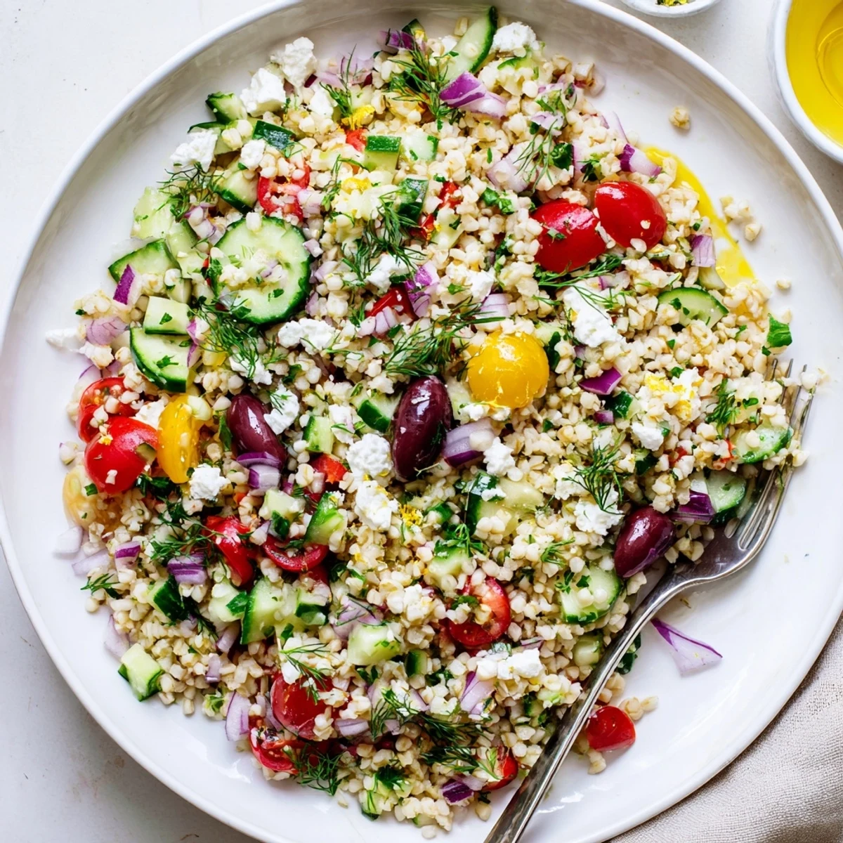 Mediterranean Bulgur and Herb Grain Salad served chilled with olives and feta, garnished with herbs and lemon wedges on the side.