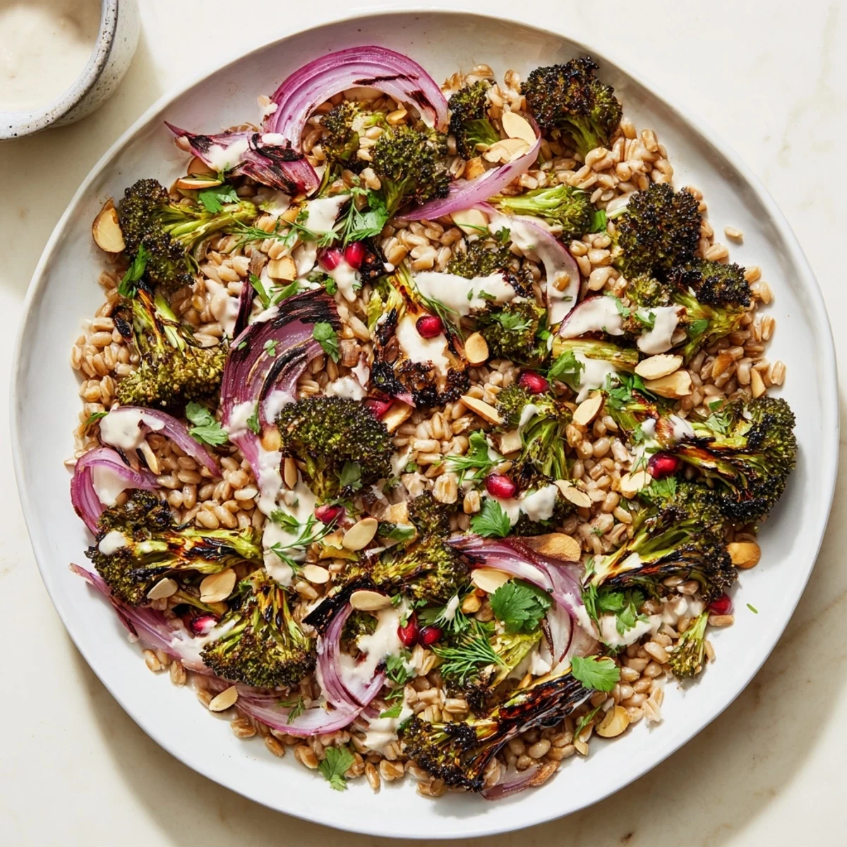 Roasted broccoli and toasted almonds garnish this Charred Broccoli and Tahini Farro Grain Salad ready to serve.