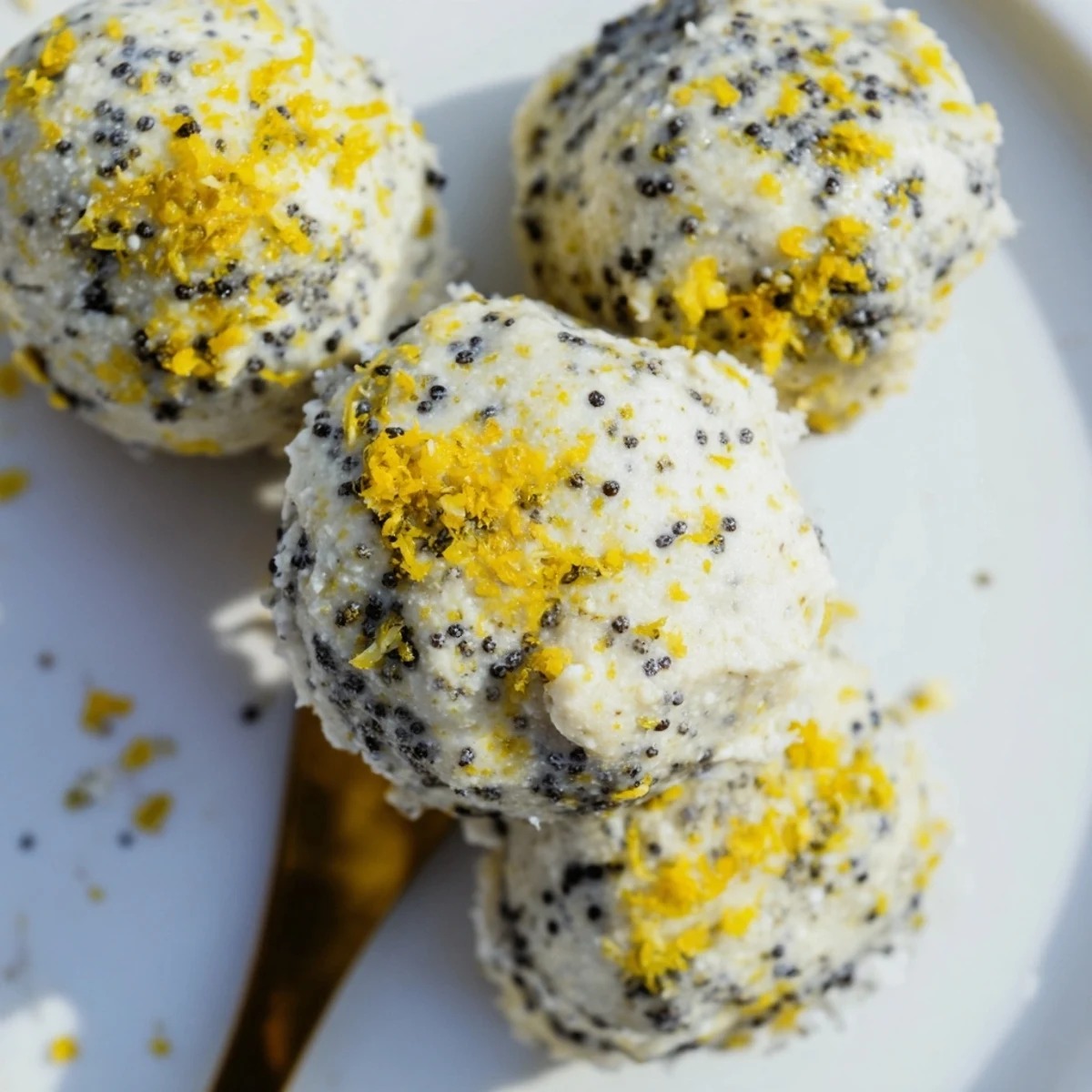 A macro shot shows the crumbly texture of Lemon Poppy Seed Cashew Bliss Sweet Treat with poppy seeds throughout.