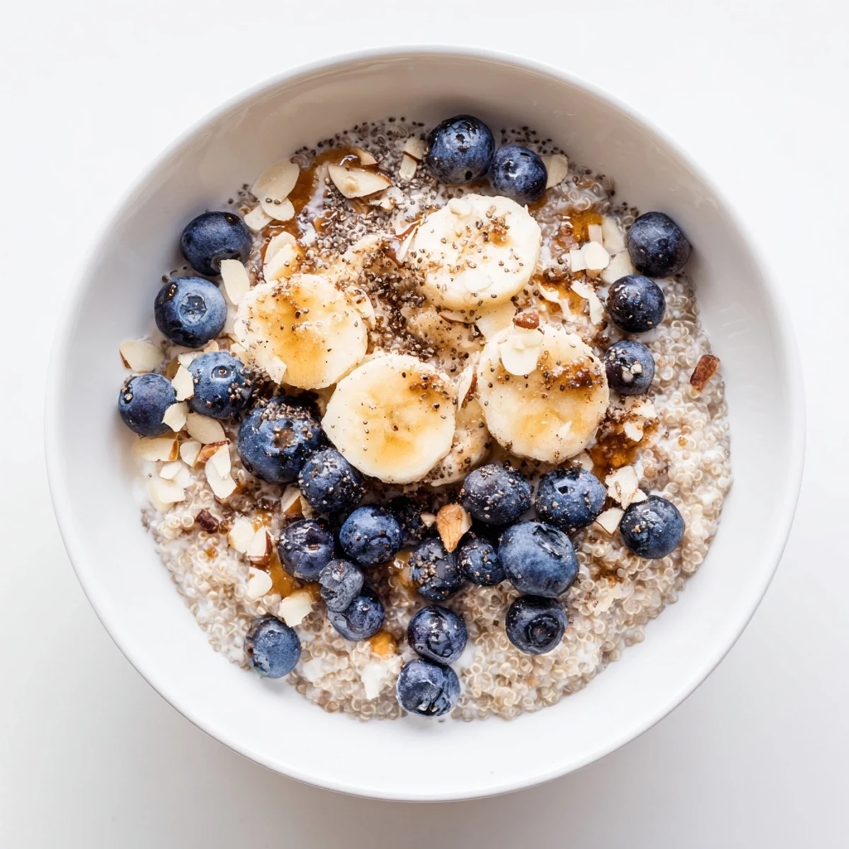 Freshly cooked quinoa mixed with cinnamon and maple syrup, layered with plump blueberries in a glass jar for a Blueberry Cinnamon Overnight Quinoa Breakfast Bowl.