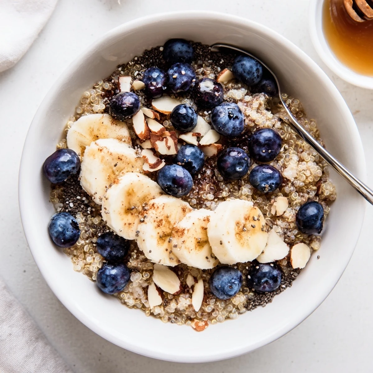 A chilled Blueberry Cinnamon Overnight Quinoa Breakfast Bowl topped with sliced banana and crunchy toasted almonds, ready for a healthy morning meal.