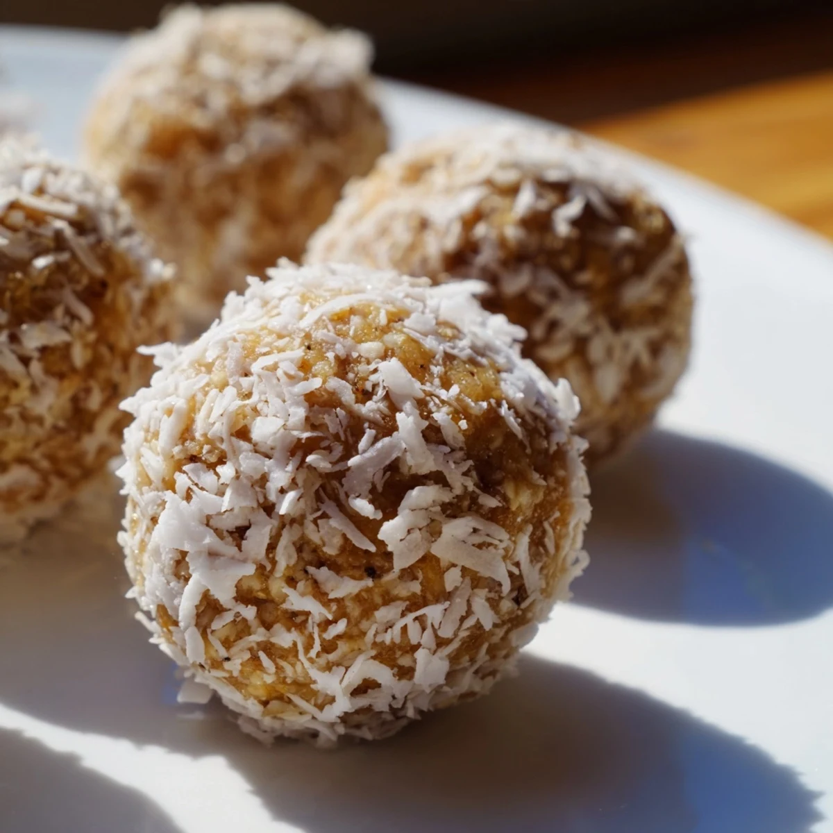 Vegan gluten-free lemon coconut bliss balls garnished with extra coconut flakes
