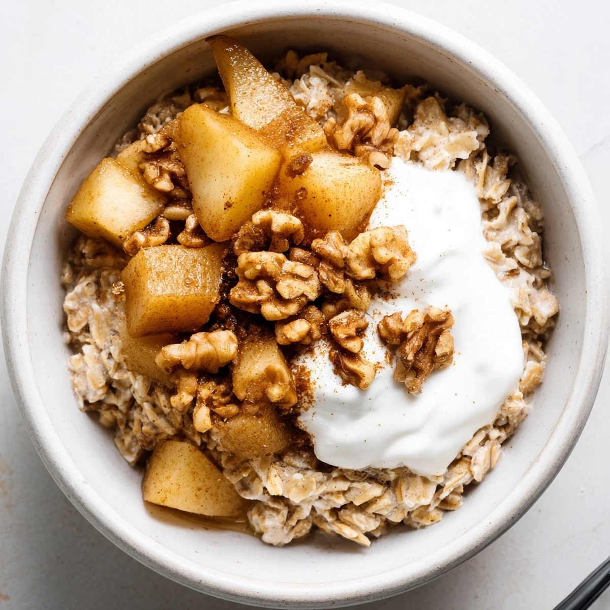 Cozy spiced pear cardamom oat breakfast bowl featuring tender cinnamon pears and maple drizzle