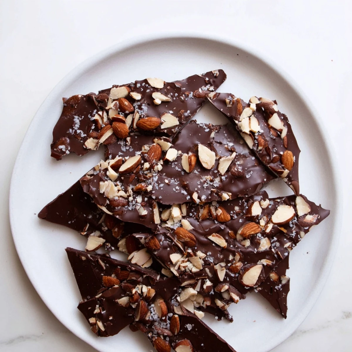 Broken pieces of salted chocolate almond freezer bark showing glossy chocolate and scattered almonds